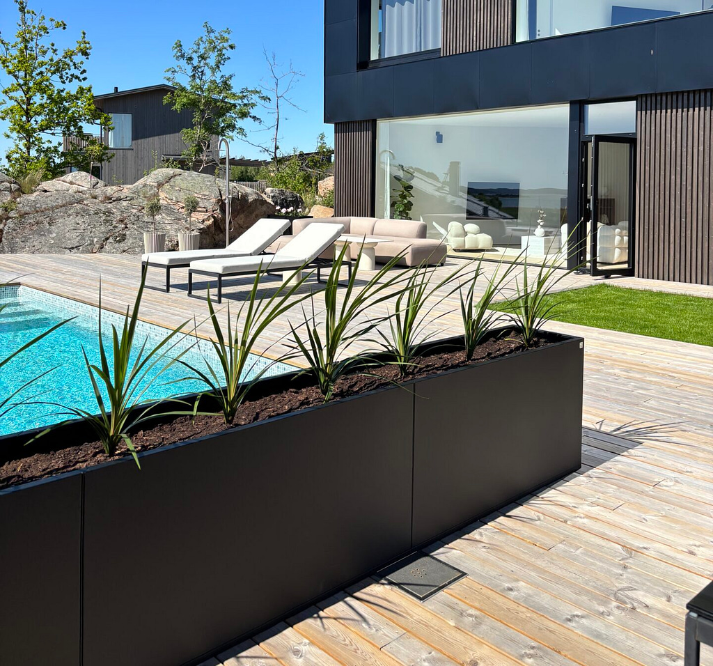 Svart Plant Box med gröna växter vid pool och modern villa