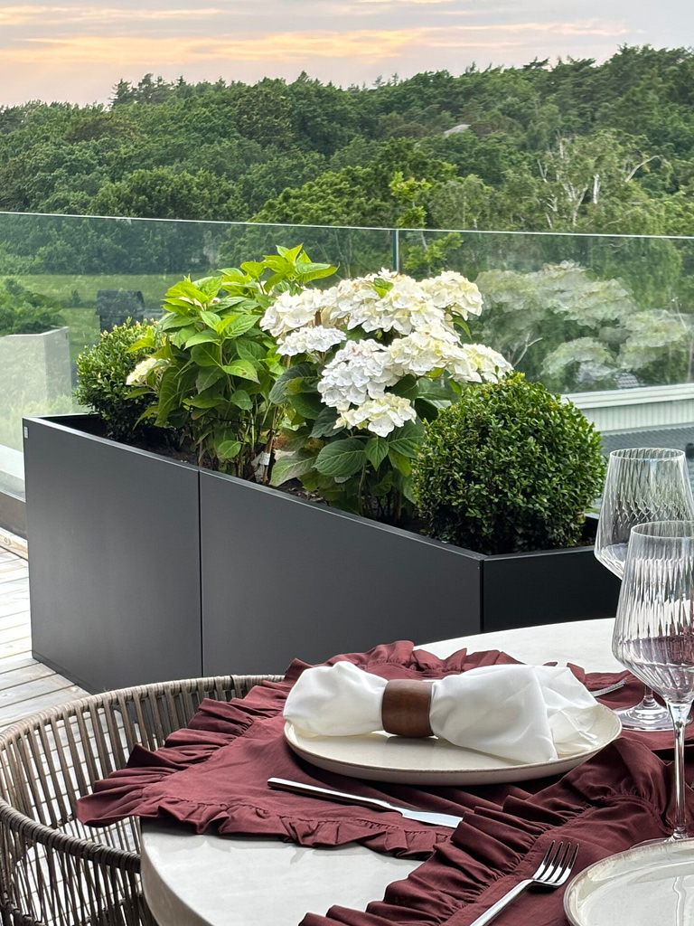 Svart Plant Box med hortensia och gröna växter på uteplats