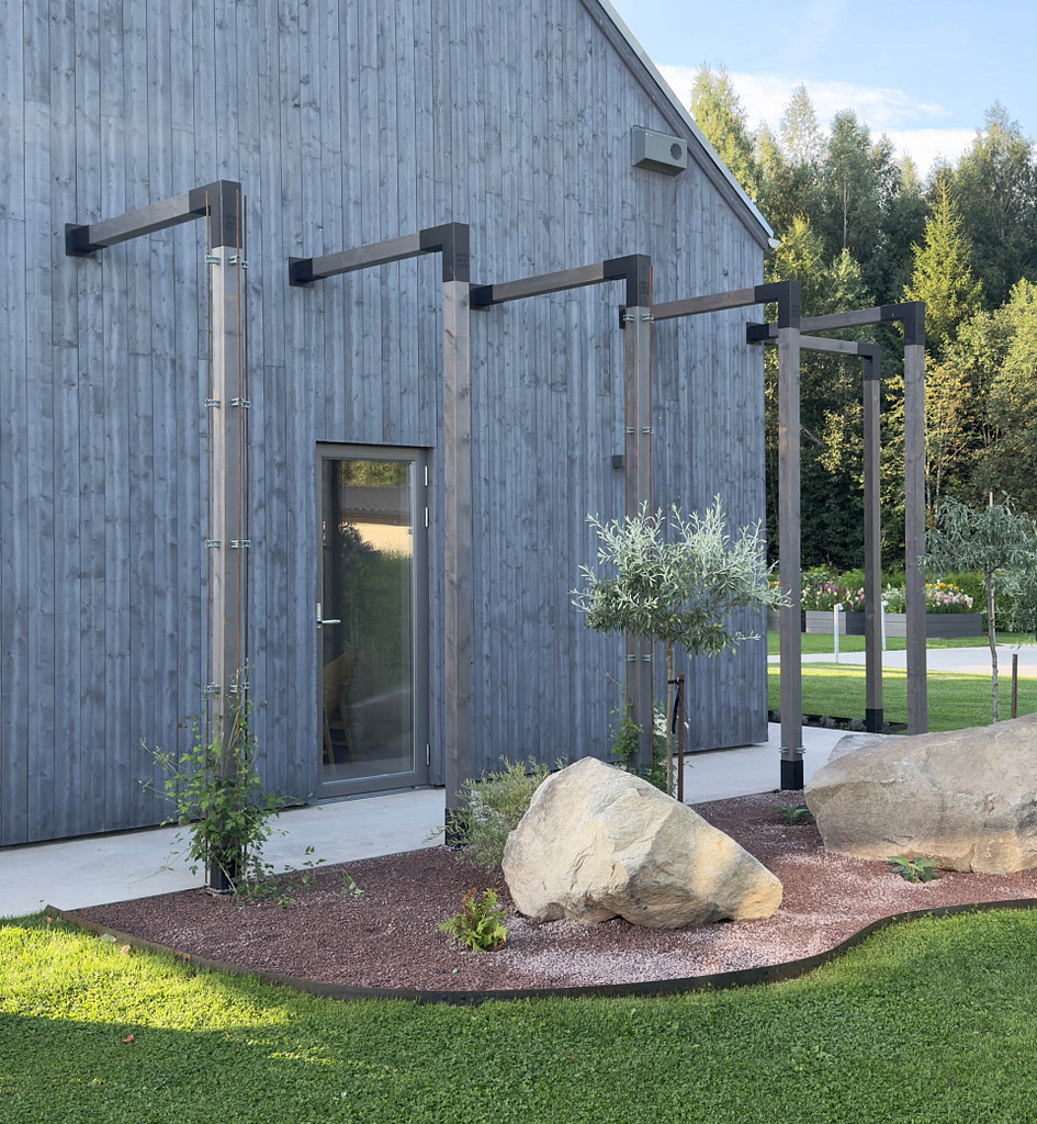 Pergolagång i trä med svarta pergolabeslag från Wernamo Design längs husfasad
