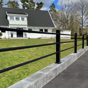 Svart staket med liggande rör framför en vit villa.