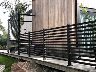 Helsvart staket Nydala omger en modern villa med träfasad.