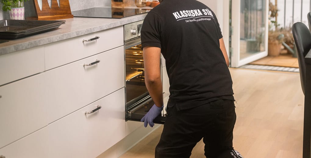 Professionell städare torkar ur ugnen under flyttstädning.