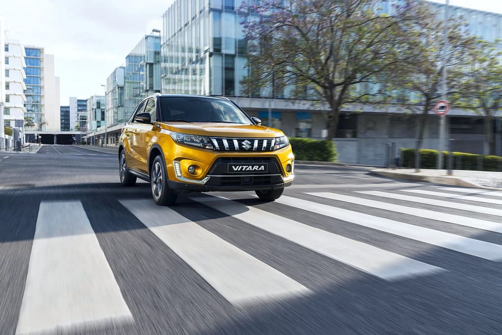 En gul Suzuki Vitara kör fort inne i en stadskärna.