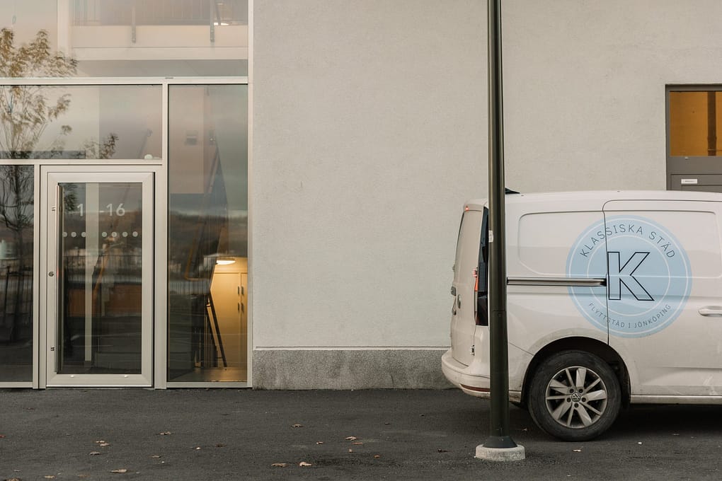 Transportbil med klassiska städs logga på sidan står parkerad utanför en byggnad.