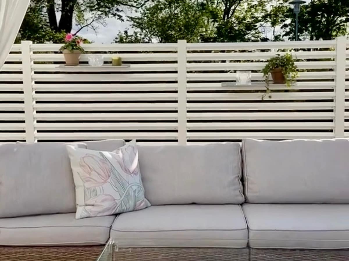 Mysig uteplats med en rumsavdelare av ett vitt staket för att få en ombonad känsla.