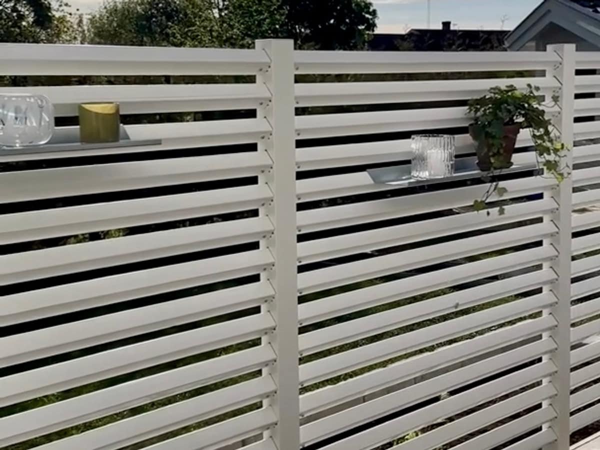 Hyllor på ett högre vitt staket på altanen.