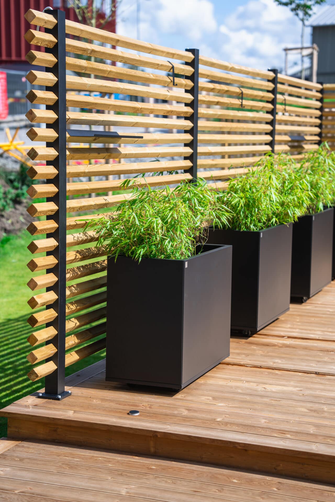 Drömminge staketstolpe med vriden 2-tums regel (45x45 mm), med Plant Boxar med planterad bambu i kruka. En svenskproducerad, underhållsfri lösning för avskärmning och vindskydd – vintergrönt och stilrent.