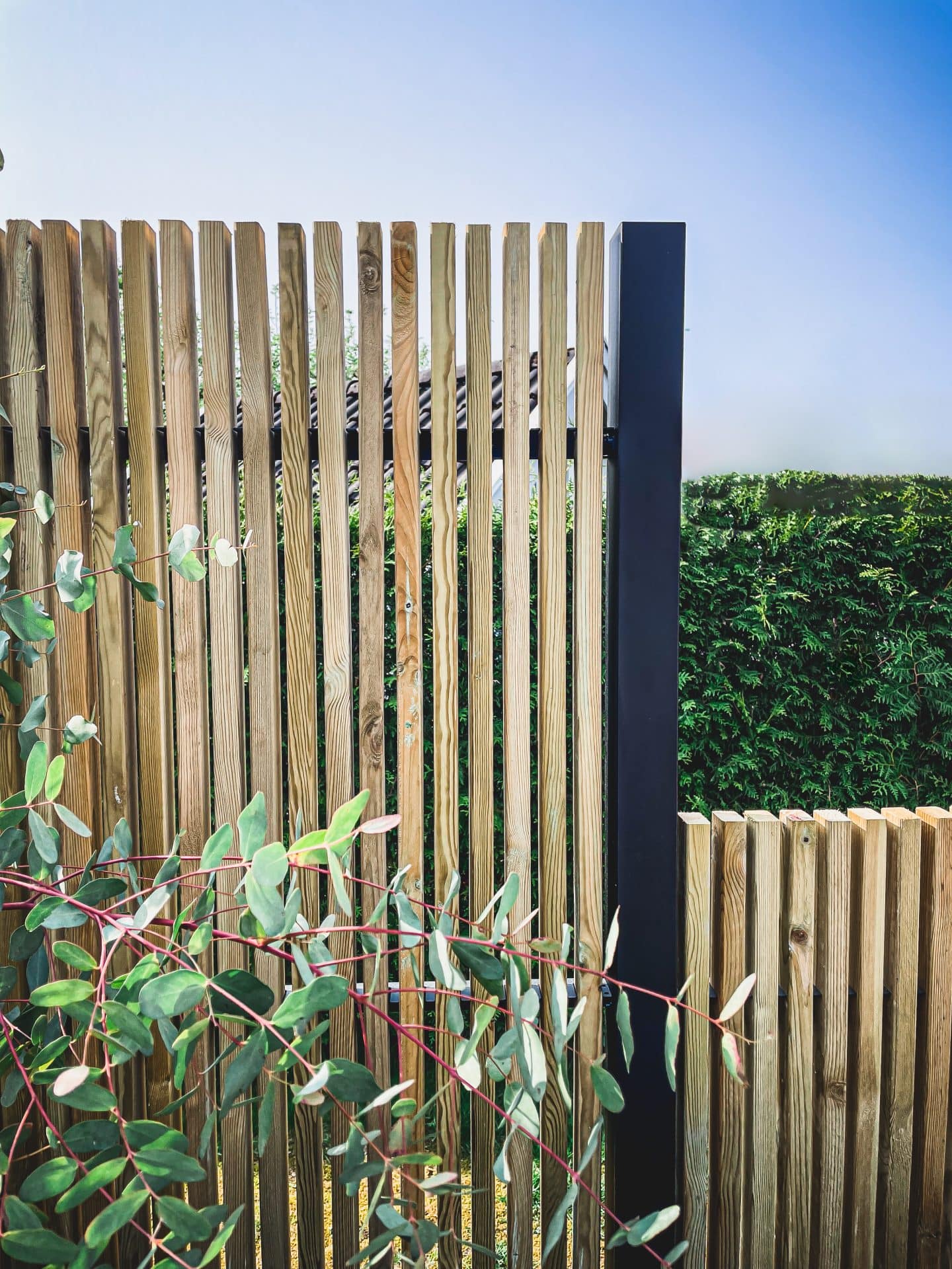 Närbild av ribbstaket Borgen som har svart stolpe och träribbor