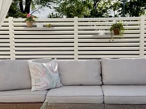 Mysig uteplats med en rumsavdelare av ett vitt staket för att få en ombonad känsla.