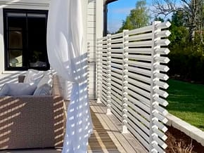 Avskärmnings vägg på uteplatsen av ett vitt staket.