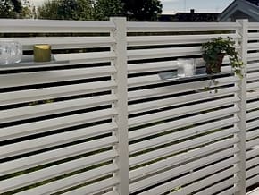 Hyllor på ett högre vitt staket på altanen.