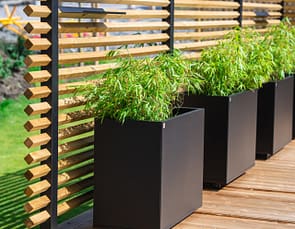 Drömminge staketstolpe med vriden 2-tums regel (45x45 mm), med Plant Boxar med planterad bambu i kruka. En svenskproducerad, underhållsfri lösning för avskärmning och vindskydd – vintergrönt och stilrent.