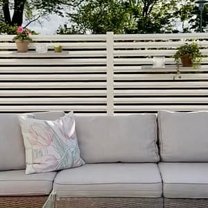 Mysig uteplats med en rumsavdelare av ett vitt staket för att få en ombonad känsla.