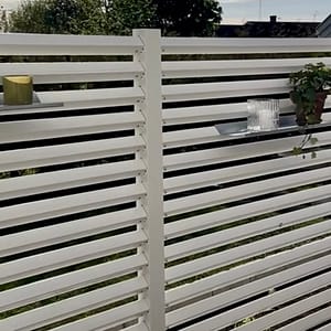 Hyllor på ett högre vitt staket på altanen.