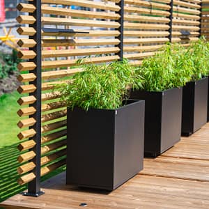Drömminge staketstolpe med vriden 2-tums regel (45x45 mm), med Plant Boxar med planterad bambu i kruka. En svenskproducerad, underhållsfri lösning för avskärmning och vindskydd – vintergrönt och stilrent.