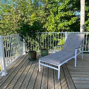 Vitt staket i modell Herrestad med solstol i förgrund.