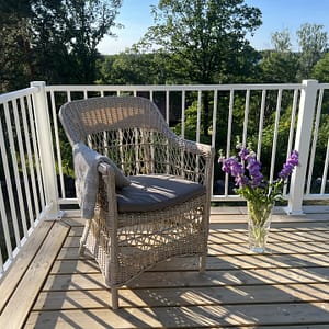 Vitt staket i modell Herrestad med stol och vas med blommor.