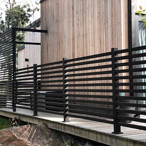 Helsort hegn Nydala omkranser en moderne villa med træfacade.