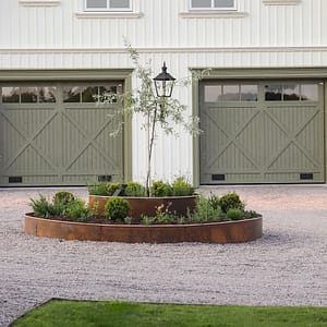 Lantligt hus med en rondell framför garaget tillverkat av en planteringsring i corten.