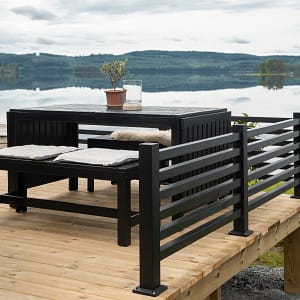 Svart staket på trädäck som har utsikt över en sjö.