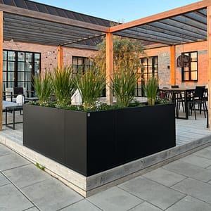 Planteringskärl i form av Plant Box ramar in hörnet på en uteplats.