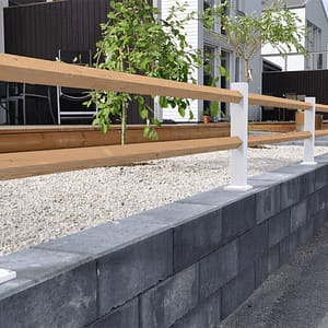 Vitt lågt staket med träreglar ovanpå en mur.