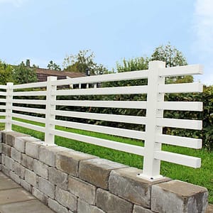 Helvitt staket på en mur i en trädgård.