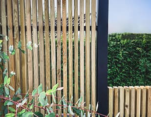 Närbild av ribbstaket Borgen som har svart stolpe och träribbor