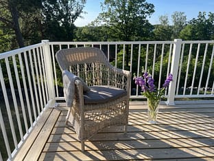 Vitt staket i modell Herrestad med stol och vas med blommor.