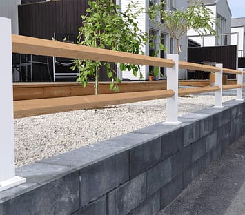 Vitt lågt staket med träreglar ovanpå en mur.