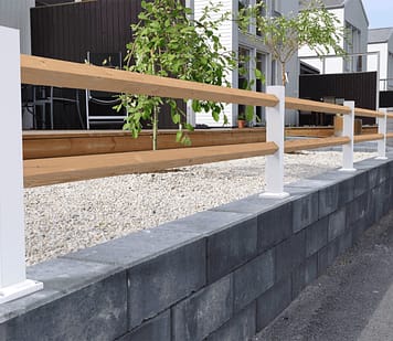 Hvidt lavt hegn med træstænger på toppen af en mur.