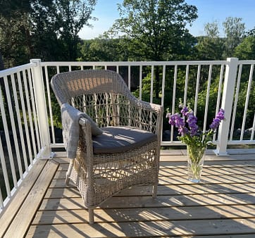 Vitt staket i modell Herrestad med stol och vas med blommor.