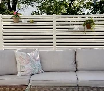 Mysig uteplats med en rumsavdelare av ett vitt staket för att få en ombonad känsla.