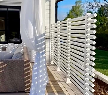 Avskärmnings vägg på uteplatsen av ett vitt staket.