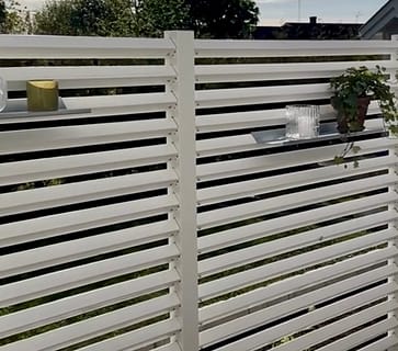 Hyllor på ett högre vitt staket på altanen.