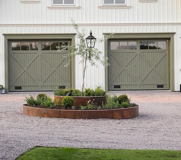 Lantligt hus med en rondell framför garaget tillverkat av en planteringsring i corten.