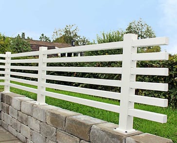 Helvitt staket på en mur i en trädgård.