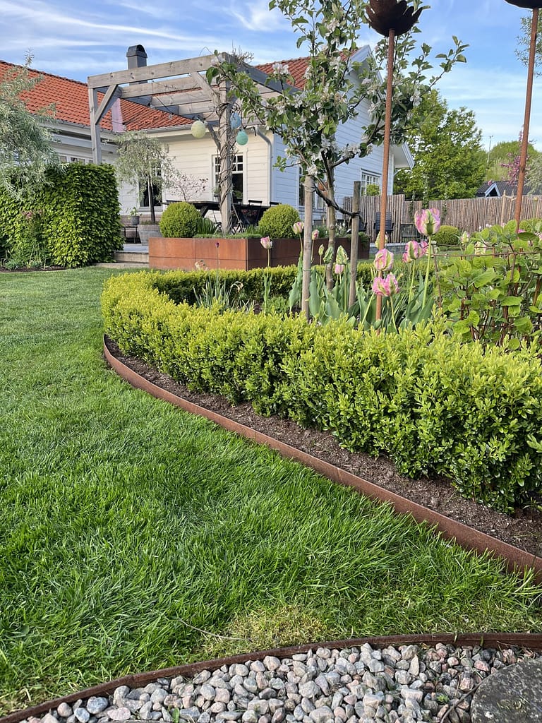 Snygg rabattkant i corten som ramar in rabatten och avgränsar gräs.