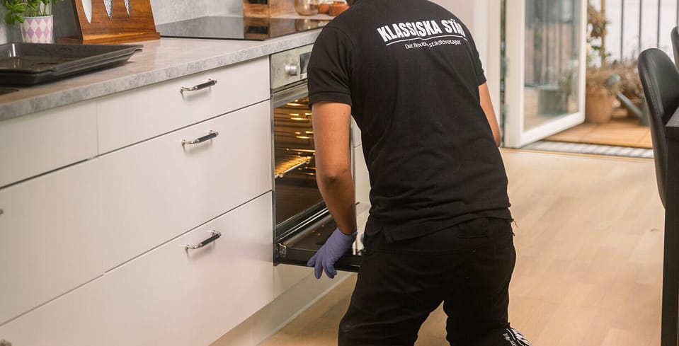 Professionell städare torkar ur ugnen under flyttstädning.